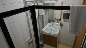 A modern bathroom with a glass shower enclosure, a toilet, a sink with a mirror, and a towel rack. - Esen Life Hotel  (Istanbul)