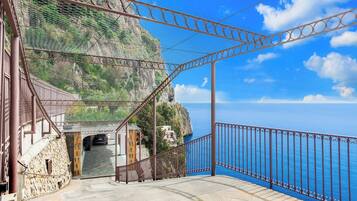 A coastal entrance with a metal gate, stone steps, and a view of the sea.