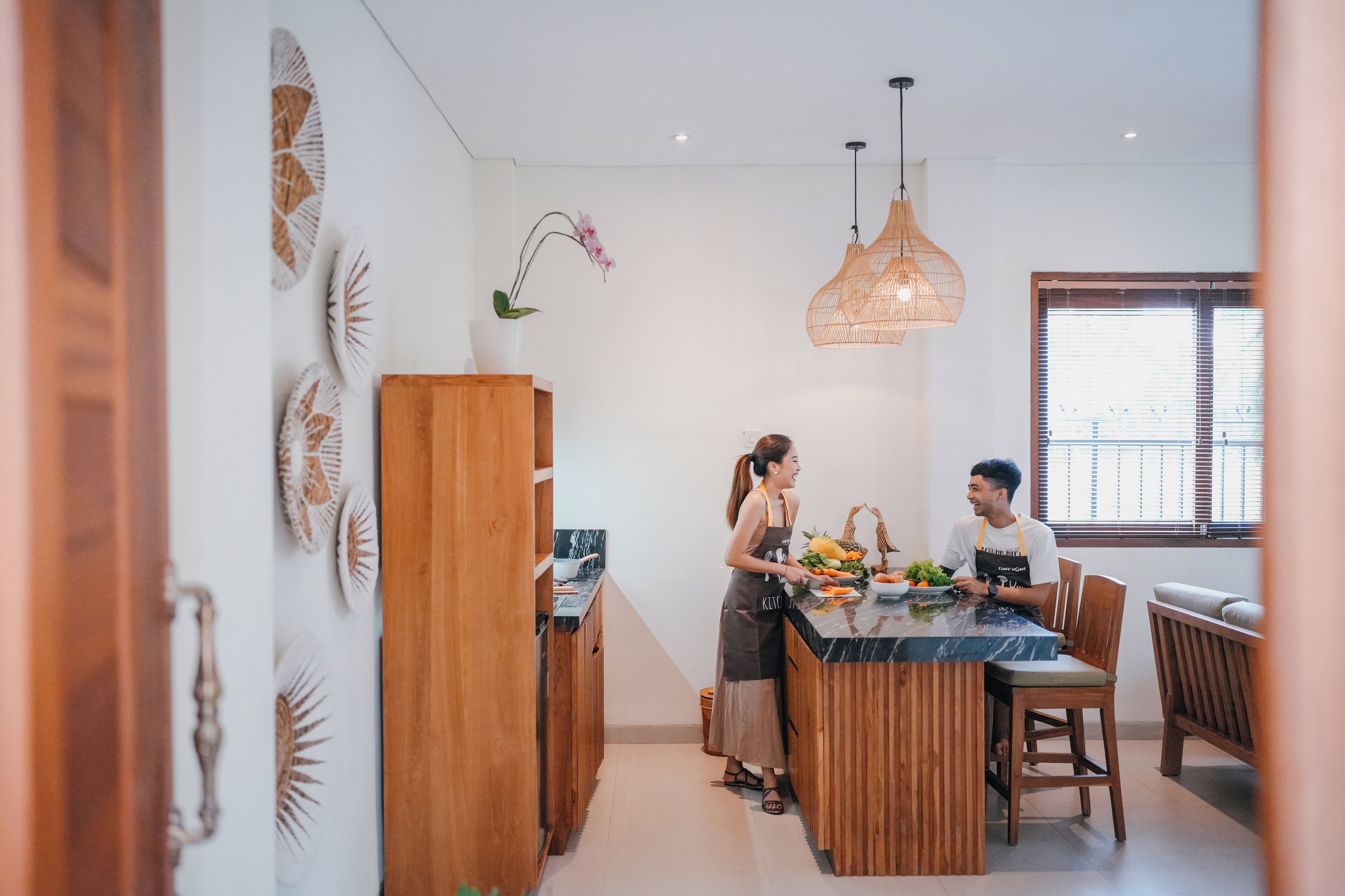 Eine moderne Küche mit Holzschränken, einer Marmorarbeitsplatte und einer Hängeleuchte.