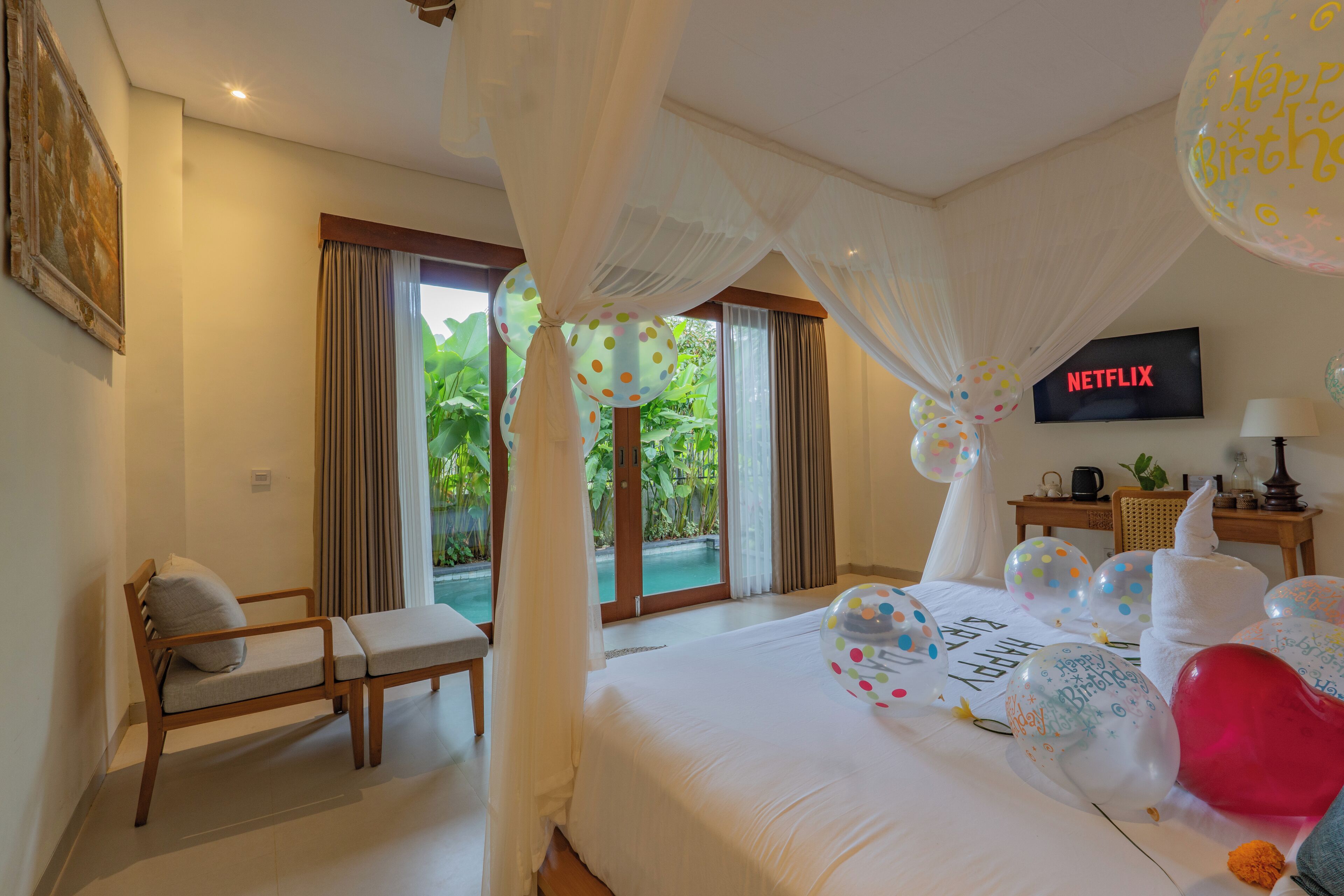 A hotel room with a bed, a chair, a TV, and a view of a swimming pool.