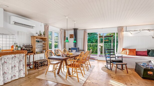 Amplia sala de estar con mesa y sillas de comedor, un sofá y una zona de cocina con horno empotrado y estanterías.