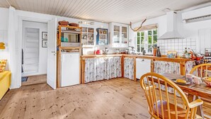 Una cocina luminosa con armarios blancos, una mesa de comedor de madera y una silla amarilla.