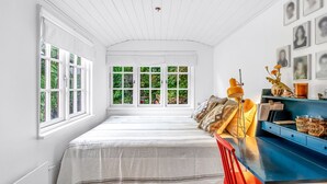 Una habitación amplia con una cama grande, un escritorio con silla y una ventana con vistas a zonas verdes.