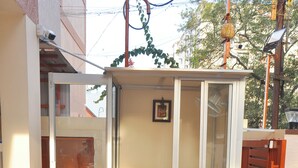 A small, enclosed outdoor space with a single chair, a window, and a door. - Harikrishna Park  (Coimbatore)