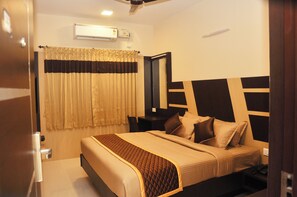 A hotel room with a bed, bedside table, and an air conditioning unit. - Harikrishna Park (Coimbatore)