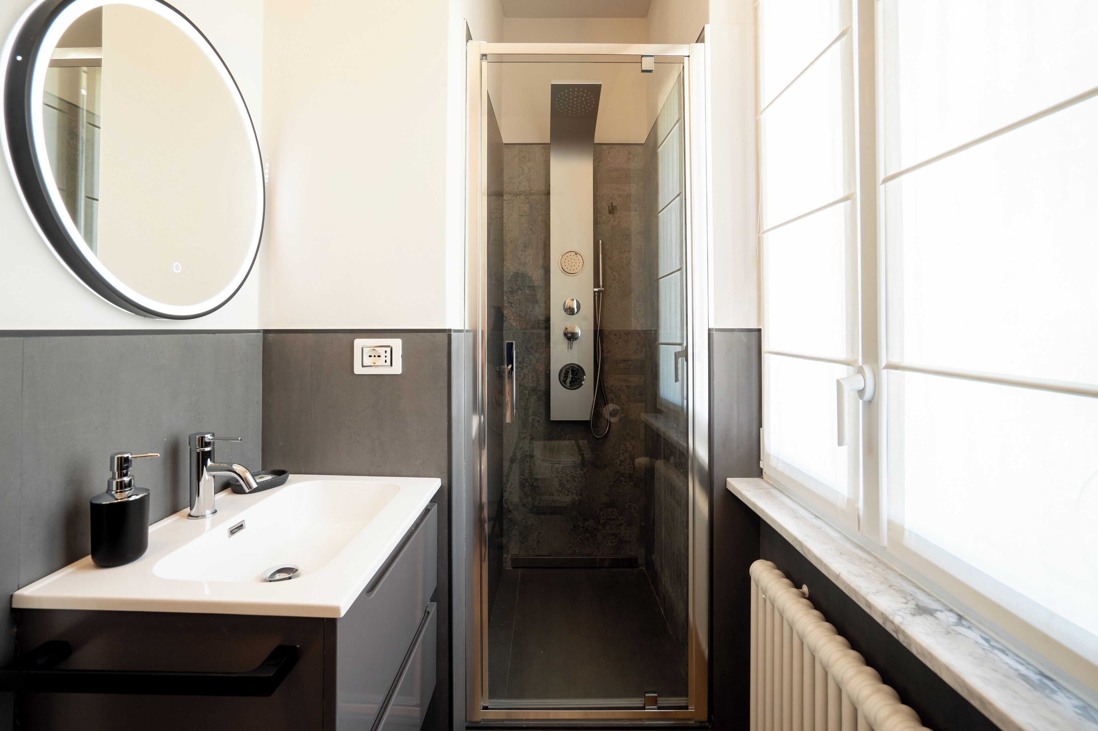 Un bagno moderno con lavandino, specchio e doccia.