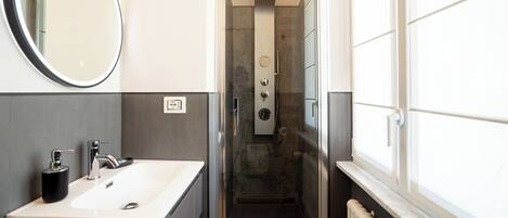 Une salle de bain moderne avec un lavabo, un miroir et une douche.