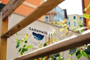 Une enseigne pour « CADAMARE », avec un logo et le texte suivant : « DES CHAMBRES RAVISSANTES À PORTOVENERE ».