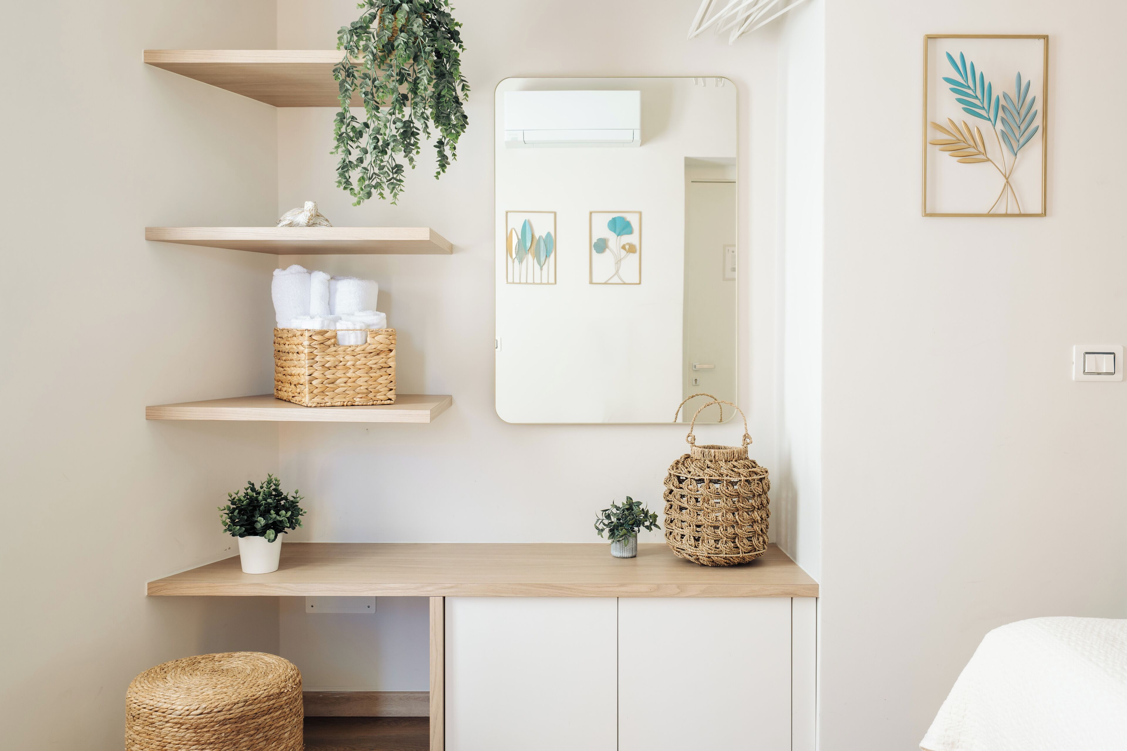 A bathroom with a wooden vanity, a mirror, and shelves with towels and baskets.