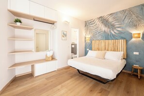 A bedroom with a bed, wooden shelves, a mirror, a wall-mounted light, and a door. - CADAMARE charming rooms in Portovenere (La Spezia)