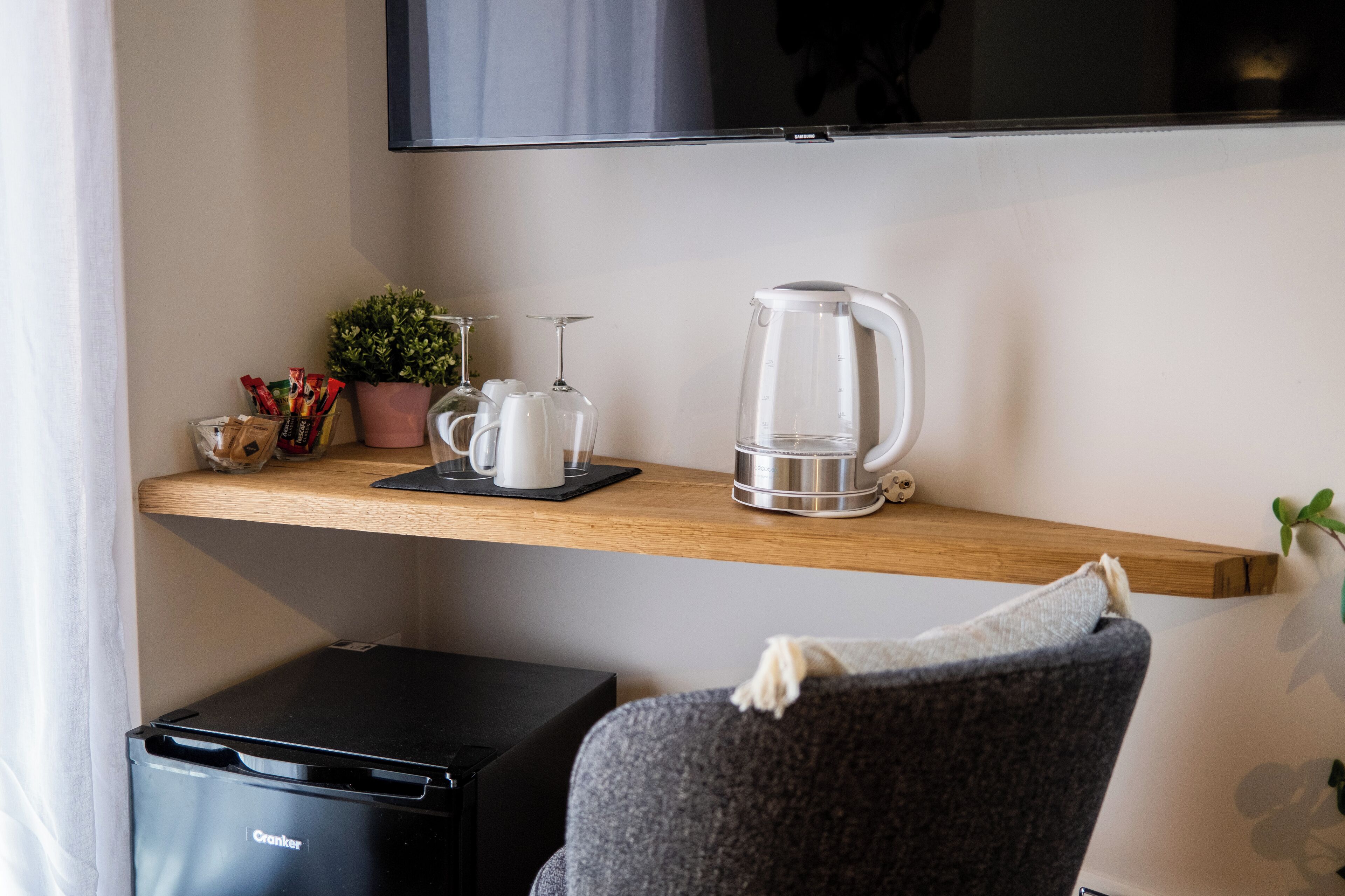 Eine moderne Küchenzeile mit Kaffeemaschine, Glasbehälter und einer kleinen Topfpflanze auf einem Holzregal.