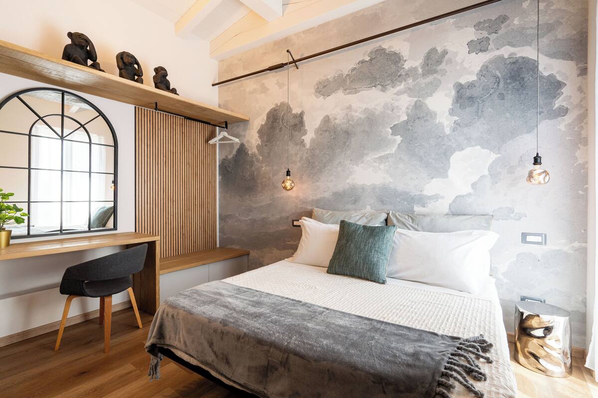 Een slaapkamer met een bed, een bureau, een stoel en een raam.