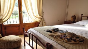 Ein Schlafzimmer mit einem hölzernen Bett, einem gewebten Hocker und einem Korbwannenkorb mit Blumen auf dem Bett.