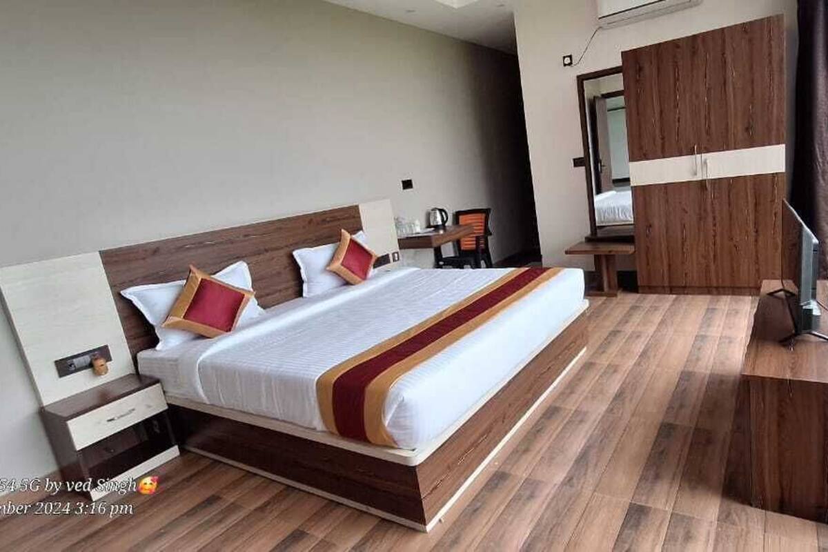 Un dormitorio moderno con una cama grande, suelo de madera, un escritorio y vistas a zonas verdes.