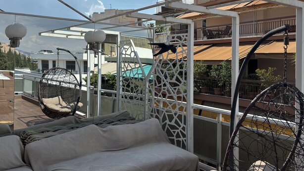 Terraza en la azotea con mobiliario exterior, que incluye una hamaca colgante y un sofá con cojines.