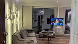 Una sala moderna con sofá, una mesa de centro y un televisor mostrando un noticiero.