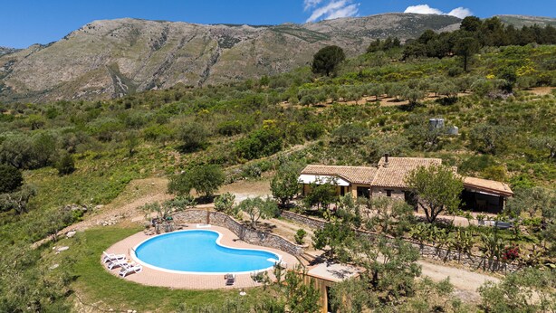 A villa with a swimming pool surrounded by a stone wall, set against a mountainous backdrop. - Villa Granci con Piscina by Wonderful Italy (Polizzi Generosa)