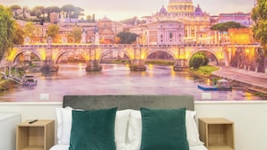 Un dormitorio con un mural de un paisaje urbano, una cama con almohadas verdes y blancas, y dos mesitas de noche.