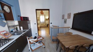 Een kleine keuken met een eethoek, een magnetron, een gasfornuis en een kleine eettafel met stoelen.