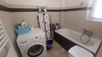 A compact bathroom with a Bosch washing machine, a bathtub, and a shower.