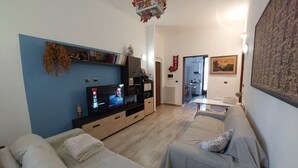 Een woonkamer met een televisie, banken, een salontafel en een keuken op de achtergrond.