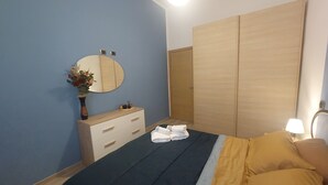 Een slaapkamer met een bed, een dressoir, een spiegel en een kledingkast.