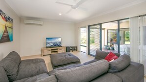 Una sala de estar moderna con un televisor de pantalla plana, sofás grises y un balcón con mobiliario exterior.