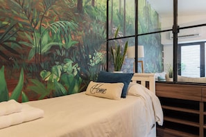 Un dormitorio con cama, un ventanal grande, vistas al exterior y un mural en la pared.