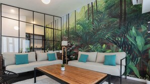 Een moderne woonkamer met een zithoek, een salontafel en een muurschildering van een bos.