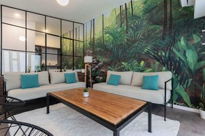 Ein modernes Wohnzimmer mit einer Sofagarnitur, einem Couchtisch und einem Wandbild von einer Waldszene.