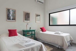 Ein Hotelzimmer mit zwei Betten, einem kleinen Tisch mit einer Lampe und gerahmten Bildern an der Wand.