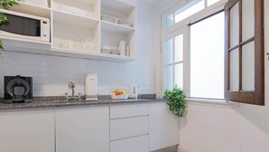 Een moderne keuken met witte kasten, een granieten aanrecht, een koffieapparaat en een raam met uitzicht.