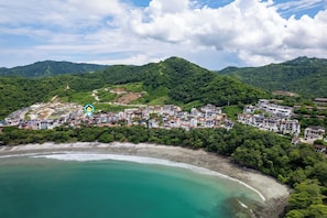 A coastal town with a beach, surrounded by hills and dense greenery. - Stylish Condo in the Heart of Las Catalinas with Vibrant Design & Exclusive Beach Club Access (Las Catalinas)