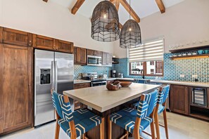 A modern kitchen with wooden cabinets, stainless steel appliances, and blue patterned backsplash. - Stylish Condo in the Heart of Las Catalinas with Vibrant Design & Exclusive Beach Club Access (Las Catalinas)