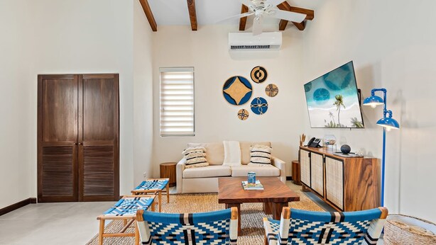 Un salon comprenant un canapé, deux fauteuils, une table basse, un téléviseur et un ventilateur de plafond.
