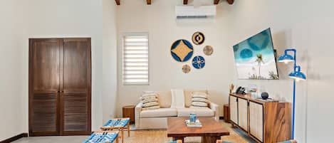 A living room with a sofa, two armchairs, a coffee table, a TV, and a ceiling fan.