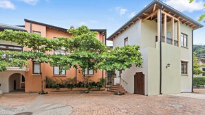 Une cour avec un sol en briques, un arbre et des bâtiments dotés de balcons et de fenêtres.