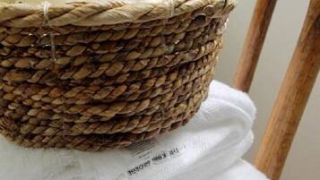 A wicker basket filled with bottles and towels placed on a chair.