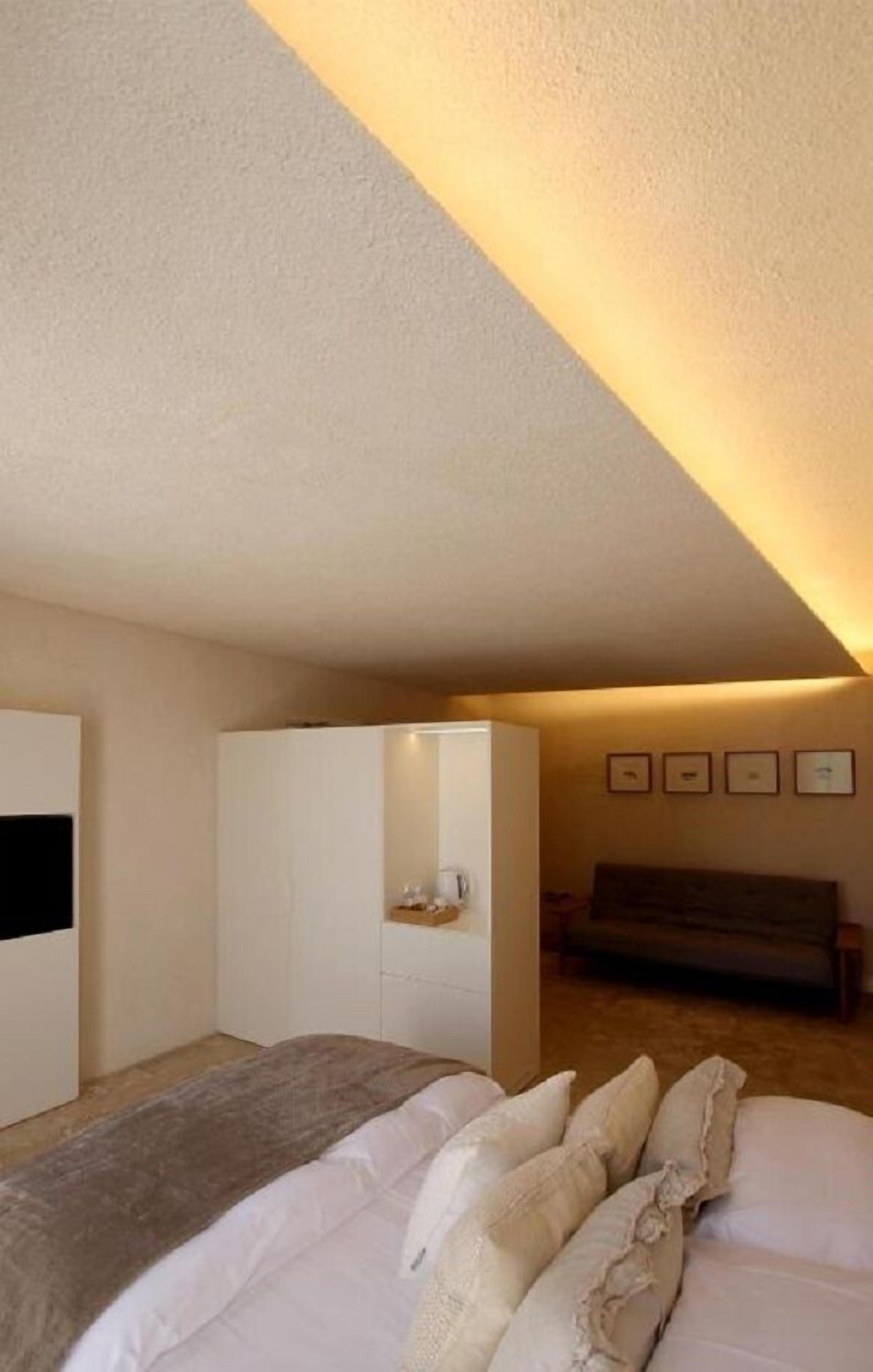 Un dormitorio con cama, armario, mesita de noche y televisor en la pared.