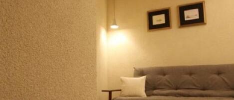 Una sala de estar con un sofá gris, una mesita y dos cuadros en la pared.