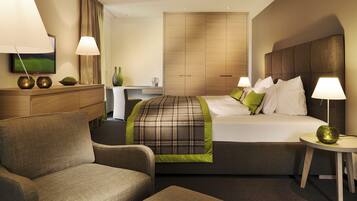 Ein Hotelzimmer mit Bett, zwei Stühlen, einem Schreibtisch und einem Fernseher.