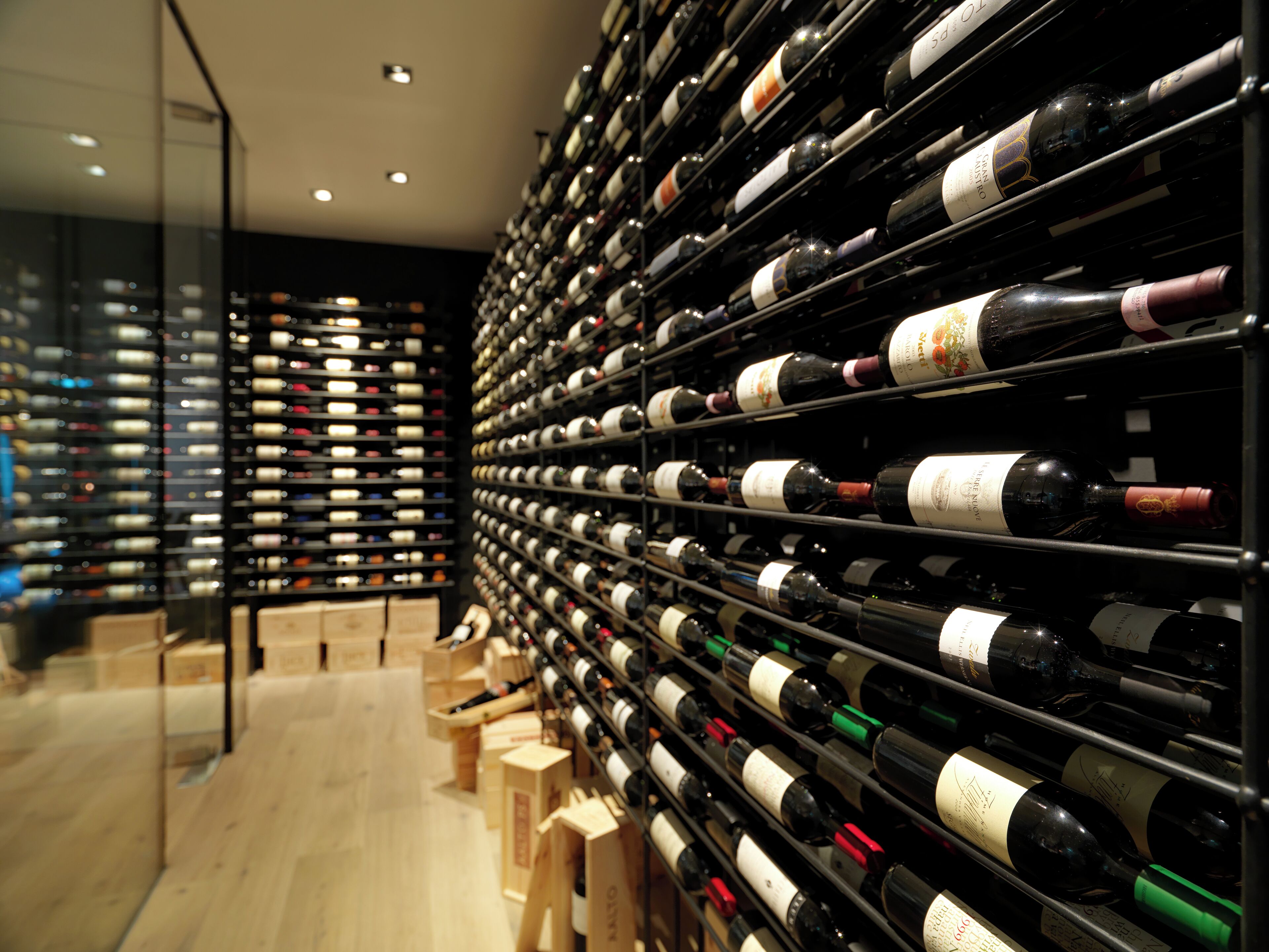 A wine cellar with numerous bottles organized on shelves.