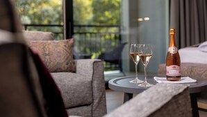 A room with a balcony, a sofa, a table with a bottle of champagne and two glasses. - Dolomitengolf Suites (Lavant)
