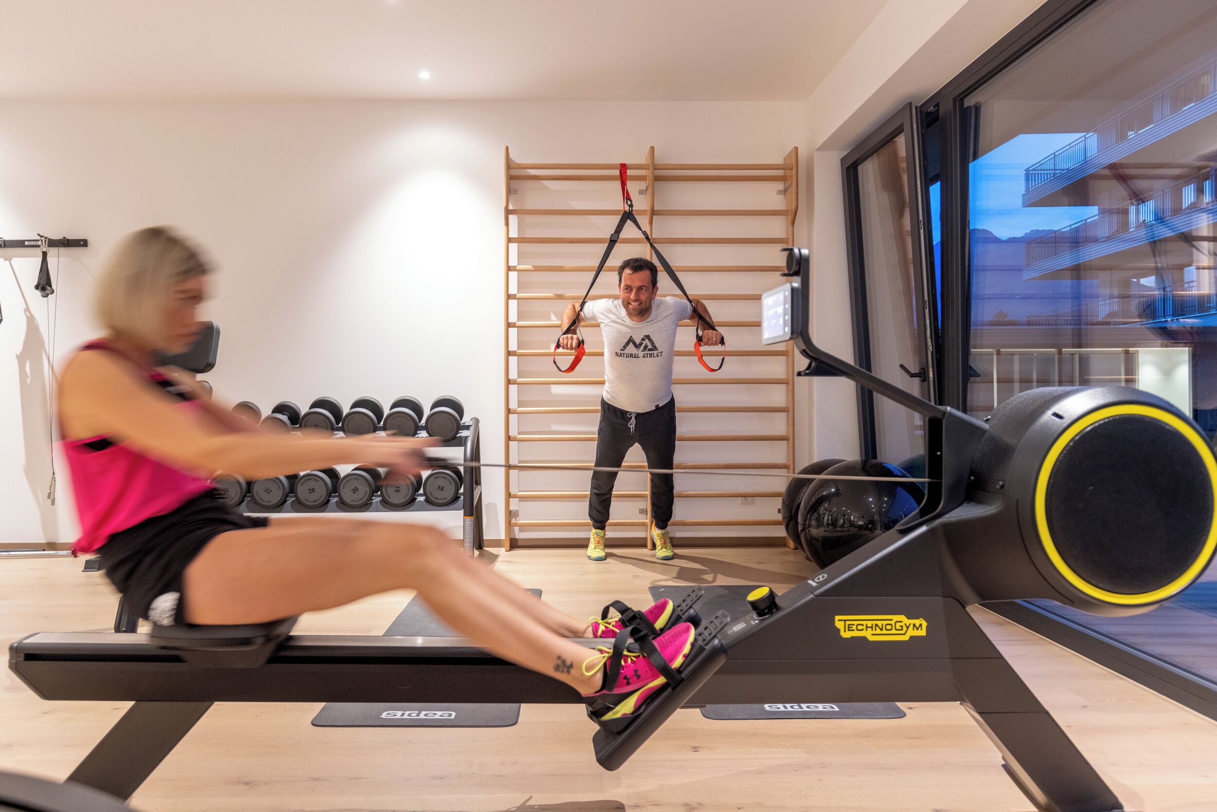 Un gimnasio con una máquina de remo, barra de dominadas y mancuernas.