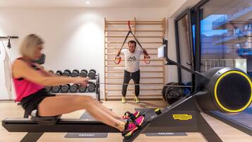 Un gimnasio con una máquina de remo, barra de dominadas y mancuernas.