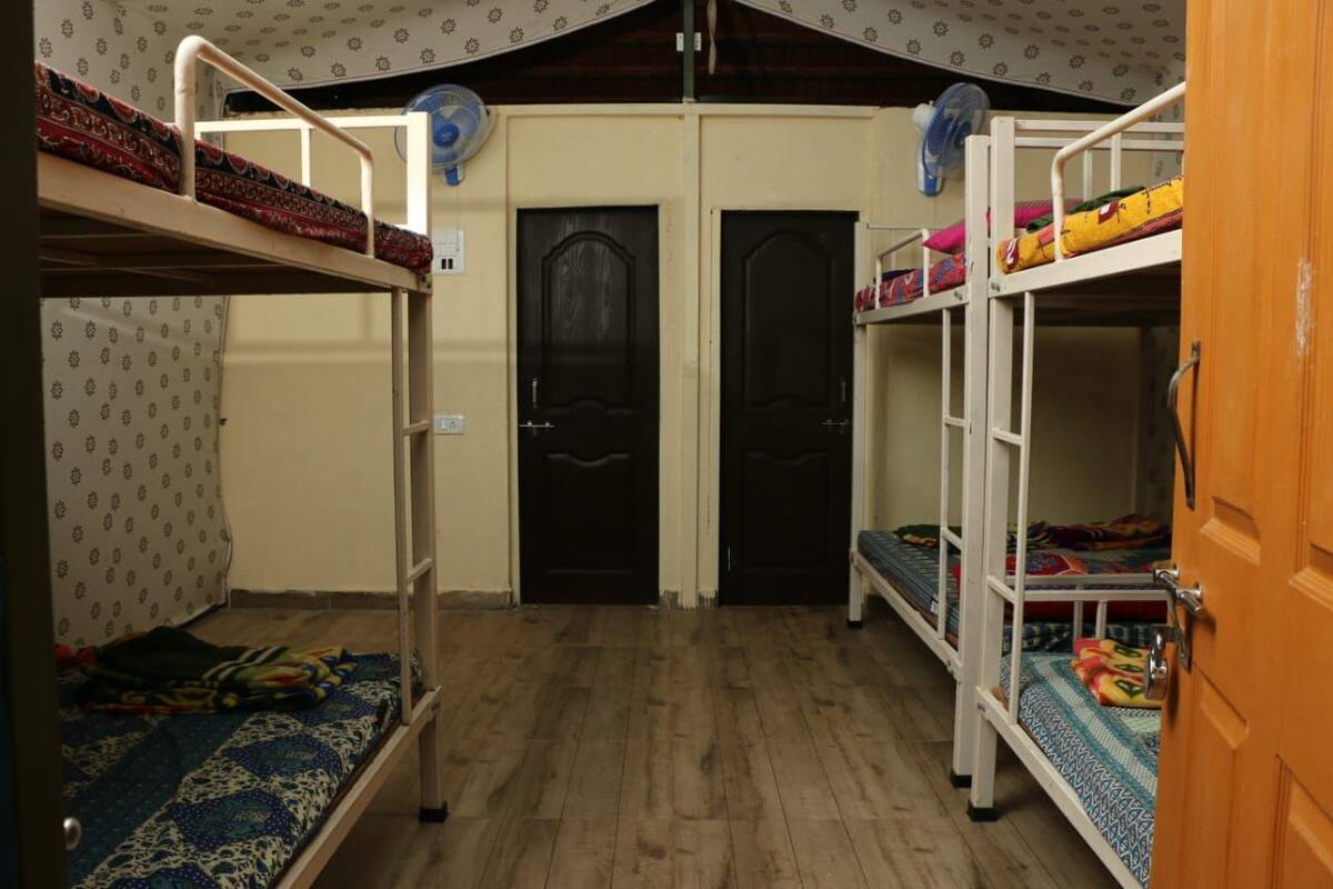 A dormitory room with bunk beds, two doors, and a wooden floor.