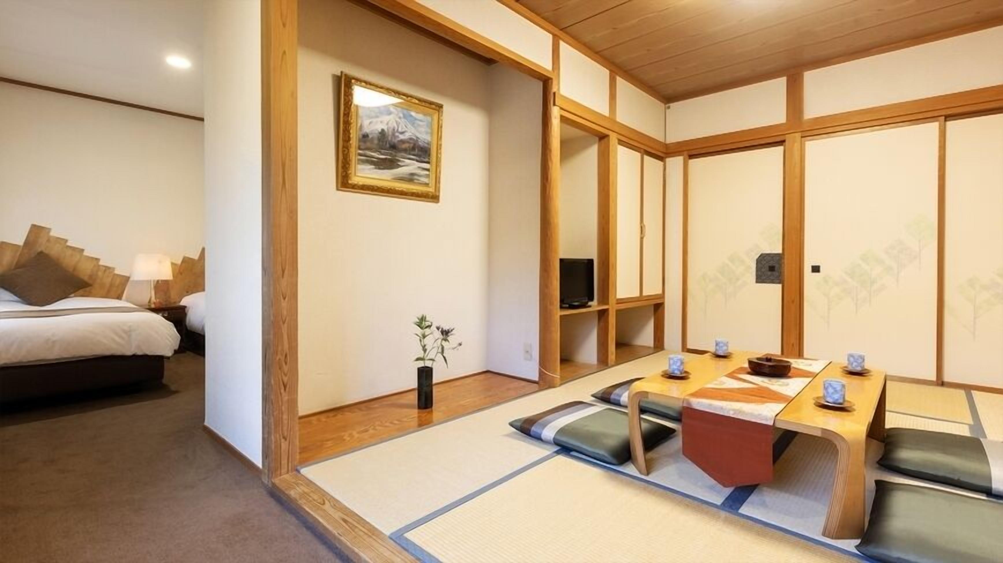 Et traditionelt japansk rum med tatamimåtter, et lavt bord med puder, en seng med sengegavl i træ og et maleri på væggen.