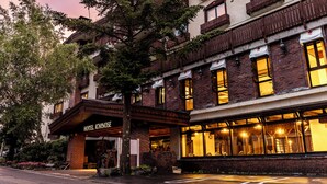 Un hôtel à la façade en briques, doté de grandes fenêtres et d’une enseigne indiquant « HÔTEL ICHINOSE ».