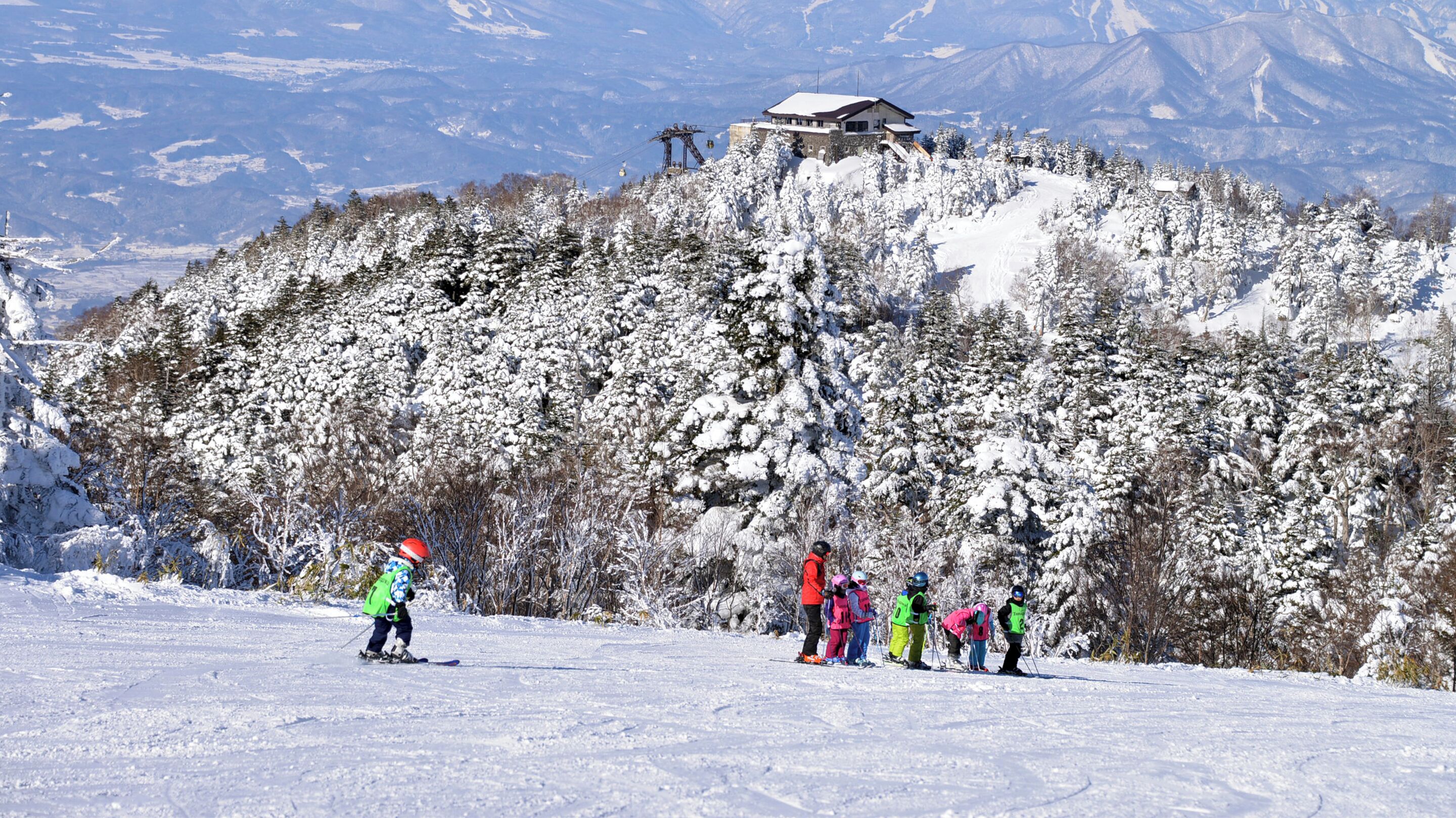 A ski resort with a mountain backdrop, a ski lift, and a lodge on a hill.
