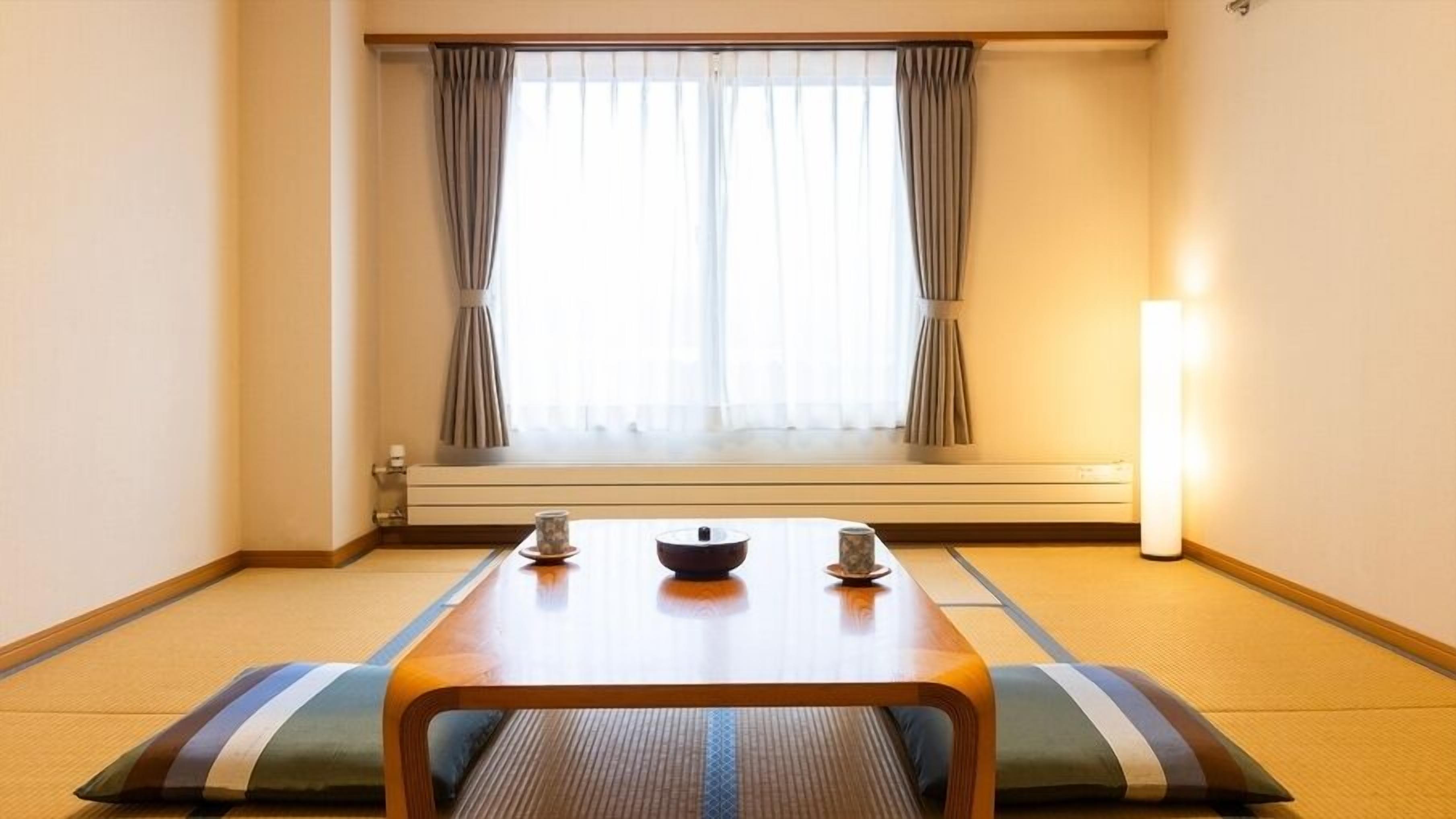 Una habitación con suelo de tatami, una mesa baja con un cuenco, dos tazas y una lámpara de pie.